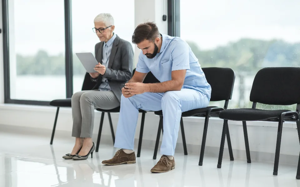 Two people seated on chairs in a clinic waiting area